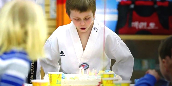 kids birthday party places near buffalo ny image of child blowing candles on cake while wearing taekwondo uniform